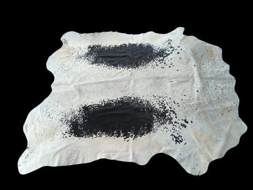 Cowhide rug with black spots on a white background